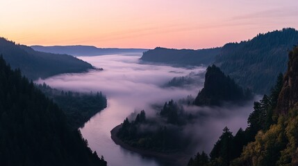 Fototapeta premium Mist gently blankets the valley while a calm river flows through dense evergreen trees. Distant mountain peaks are softly illuminated by the pale morning light