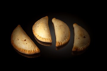 Empanadas reflecting on a dark surface
