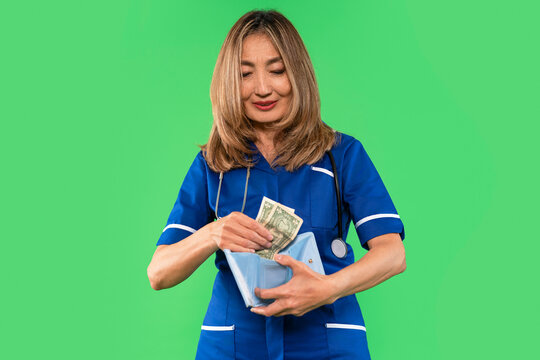 Nurse handling money in scrubs with a stethoscope on green background during a healthcare-related activity