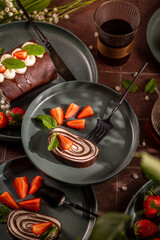 Delicious chocolate swiss roll decorated with fresh strawberries and mint