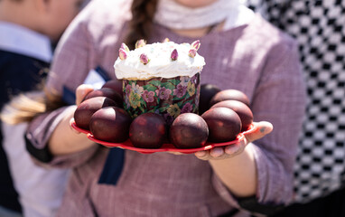 Easter cake and colored eggs in the hands of a girl