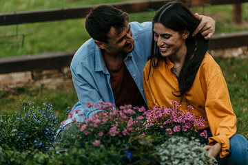 Naklejka premium Couple gardening together, planting flowers in backyard garden