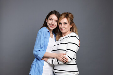 Portrait of mother and daughter on grey background