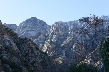 Rugged Mountain Peaks with Sparse Vegetation and a Tower Structure.