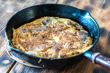 Traditional spanish breakfast potato tortilla and tostado pan con tomate. Potatoes and croutons with garlic and tomato sauce in a cast iron frying pan on a rustic wooden background. High quality photo
