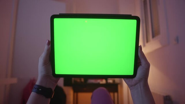 Hands holding a tablet with green screen display. Female relaxing on a sofa at home, Watching videos and reading social media or ebook. Close-up footage. High quality 4k footage