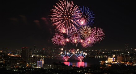 Naklejka premium Vibrant Fireworks Display Over City Skyline Illuminating Night Sky Reflecting on Water Festive Celebration Event New Year's Eve