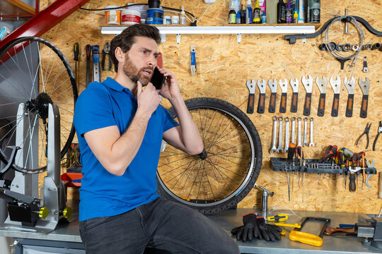 Mechanic conversing on smartphone in workshop - Powered by Adobe