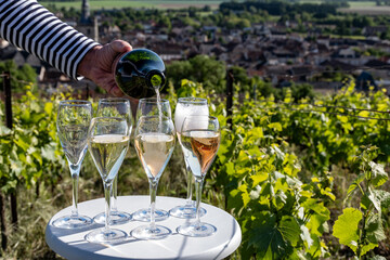 Pouring and tasting of white and rose sparkling wine brut, grand reserve, champagne in Ay-Champagne on green hilly vineyards in old wine making village in Vallee de la Marne, Champagne region, France