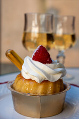 French cuisine, fresh baked baba au rum cake with chantilly cream, sweet dessert with rum and glasses of champagne wine close up