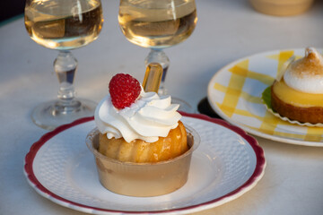 French cuisine, fresh baked baba au rum cake with chantilly cream, sweet dessert with rum and glasses of champagne wine close up