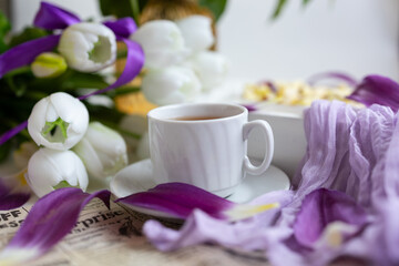 a cup of tea with cakes and a bouquet of flowers on the table