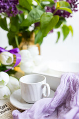 a cup of tea with cakes and a bouquet of flowers on the table