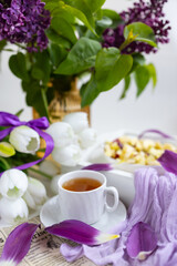 a cup of tea with cakes and a bouquet of flowers on the table