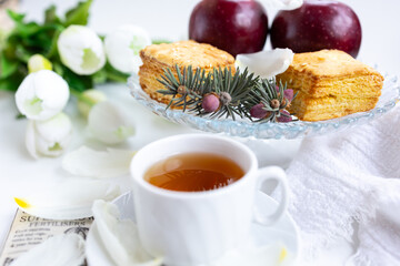 a cup of tea with cakes and a bouquet of flowers on the table
