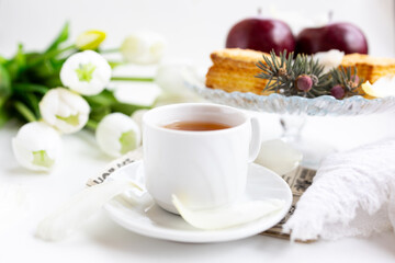 a cup of tea with cakes and a bouquet of flowers on the table