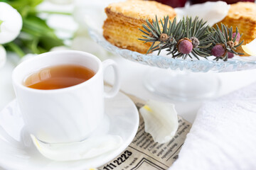 a cup of tea with cakes and a bouquet of flowers on the table