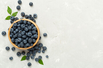 Bowl with fresh bright blueberries on concrete background,top view