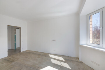The apartment hall with unfinished repairs. A doorway without a door with a bathroom view. Entrance to the kitchen.