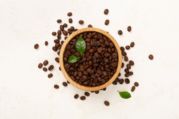 Roasted coffee beans with leaves on concrete background,top view