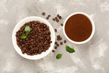 Roasted coffee beans with leaves on concrete background,top view
