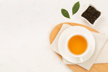 Cup of tea with dry and fresh leaves on concrete background, top view