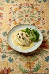 Exquisite dish of fish accompanied by a parsley sauce and fresh salad garnished with capers, beautifully presented on a colorful table setting