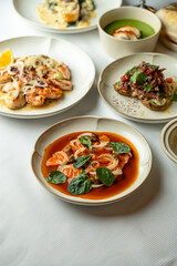 A vibrant table is adorned with a variety of exquisite dishes served at a cozy eatery. Fresh seafood and gourmet flavors come together, inviting everyone to enjoy a memorable dining experience