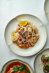A beautifully presented seafood dish showcases succulent morsels topped with fragrant herbs and fresh onion slices. The colorful plate is garnished, inviting guests to indulge in a culinary delight