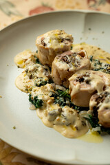 A beautifully presented dish features tender rolled protein accompanied by a rich sauce, fresh greens, and crunchy toppings, perfect for an exquisite dining experience