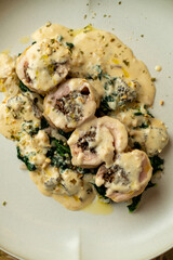 Savor the delightful presentation of a beautifully crafted dish featuring tender rolled meat, topped with a creamy sauce and accompanied by vibrant greens
