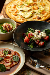 Cuisine comes alive with a vibrant spread featuring fresh salads, a gourmet pizza topped with seasonal ingredients, and expertly crafted appetizers, perfect for a delightful meal with friends