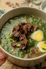 In a delightful restaurant setting, a steaming bowl of beef soup sits on a beautifully patterned tablecloth
