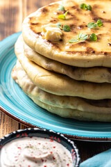 Khychins, traditional Caucasian, Eastern dish. Flatbread stuffed with minced meat with sauce on a turquoise plate with cutlery and a napkin on a wooden table. Close-up.