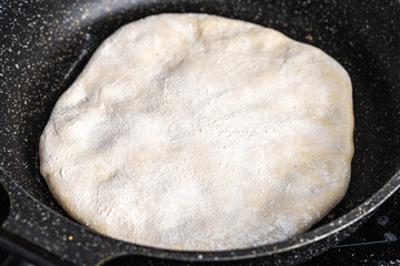 Traditional spanish breakfast potato tortilla. Potatoes in a cast iron frying pan on a rustic wooden background.