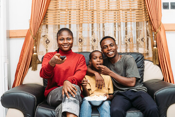 Happy Family Watching TV Together While Sharing a Snack on the Couch