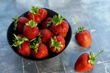 Large fresh strawberries in a bowl on a blue background