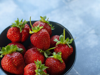 Large fresh strawberries in a bowl on a blue background