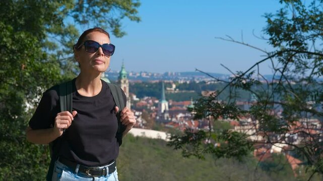 Tourist enjoying panoramic view of prague from petrin hill. Female tourist wearing backpack admires prague cityscape from petrin hill viewpoint, showcasing the city's architectural beauty