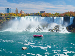 Niagara Falls. A pleasure boat with people near the huge famous waterfall. View from the Canadian side. Nature scenery. Photo for advertising, background, wallpaper, postcards.