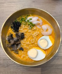 Delicious ramen with seafood and egg on wooden table
