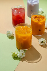 Brightly colored non-alcoholic drinks sit on a pastel surface, surrounded by delicate flowers. Perfect for a sunny afternoon gathering, these beverages offer a refreshing and delightful experience