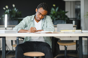 Focused university student studying and taking notes in library