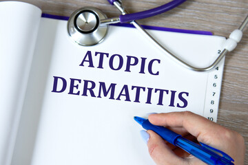 ATOPIC DERMATITIS - words in a notebook against the background of a stethoscope and a doctor's hand with a pen