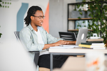 Focused university student studying on laptop in modern library