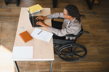 Focused student with disability using laptop in modern office