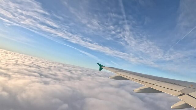 Aircraft flying above cloudscape, side window view