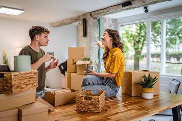 Happy couple having fun while unpack boxes together and drink coffee