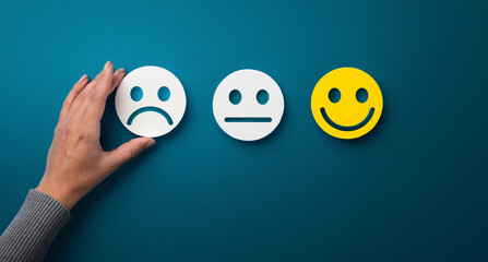 Rating concept. Woman choosing sad or bad smiley face emotion on green background, panorama, copy space