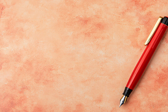 A red fountain pen rests on a textured coral colored paper providing space for calligraphy work.